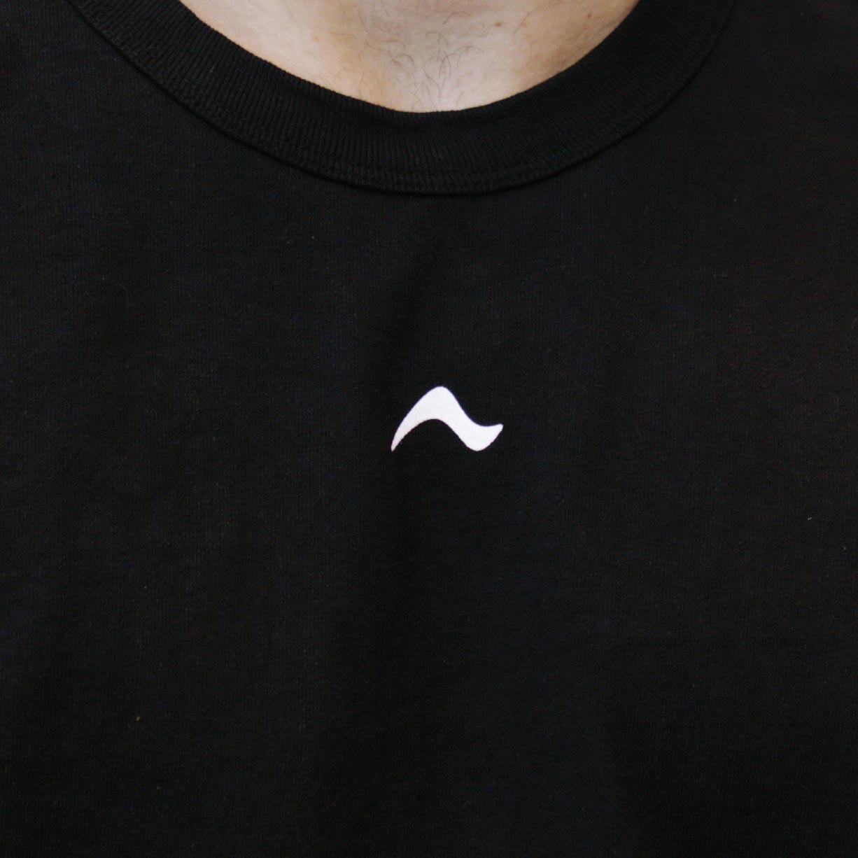 Close up of person wearing a black Arc brand mark tee shirt